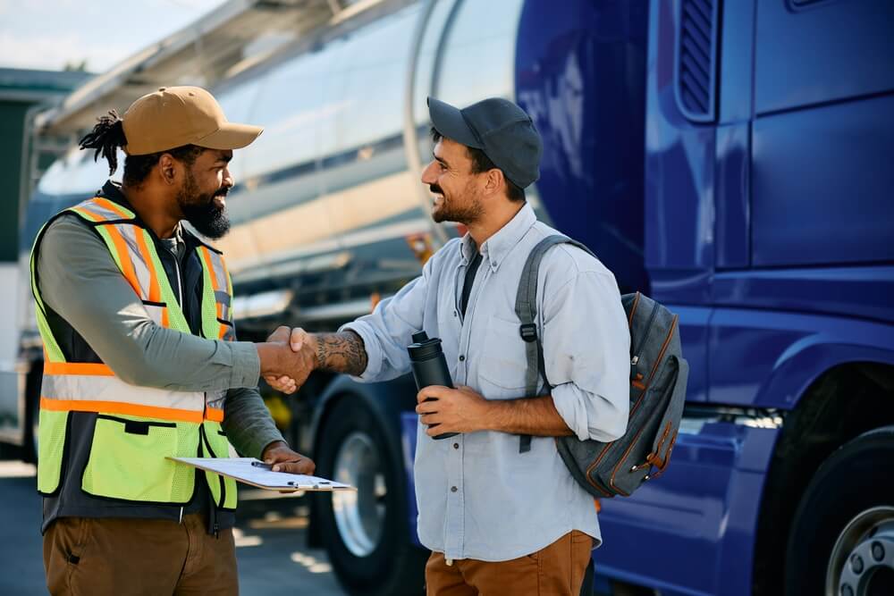 A fleet manager and truck driver shaking hands