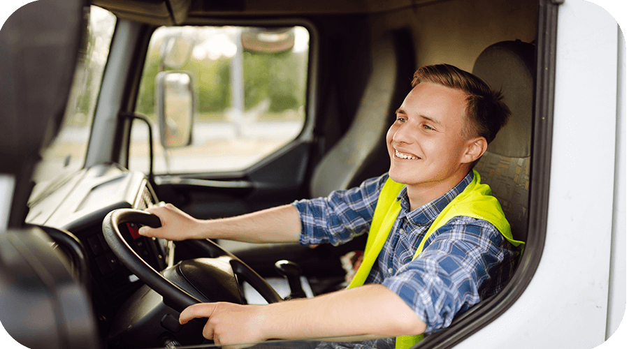 A driver sits in the cab of a commercial truck.