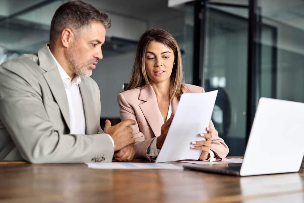 A photo of a woman discussing distracted driving risk with a man in an office
